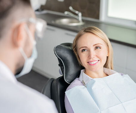 dentist speaking with woman sitting in a dental chair